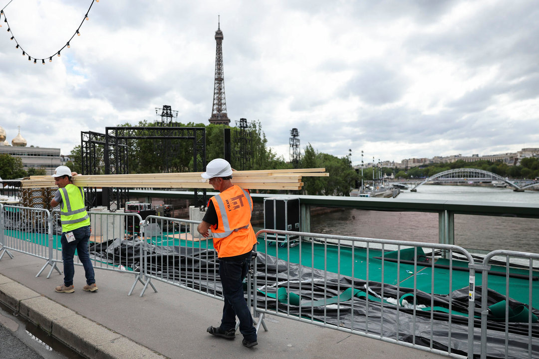 Varios operarios pasan ante el río Sena de París, este martes. El Sena será el escenario elegido para la ceremonia de inauguración de los Juegos Olímpicos el próximo viernes 26 de Julio. EFE/ Miguel Gutierre