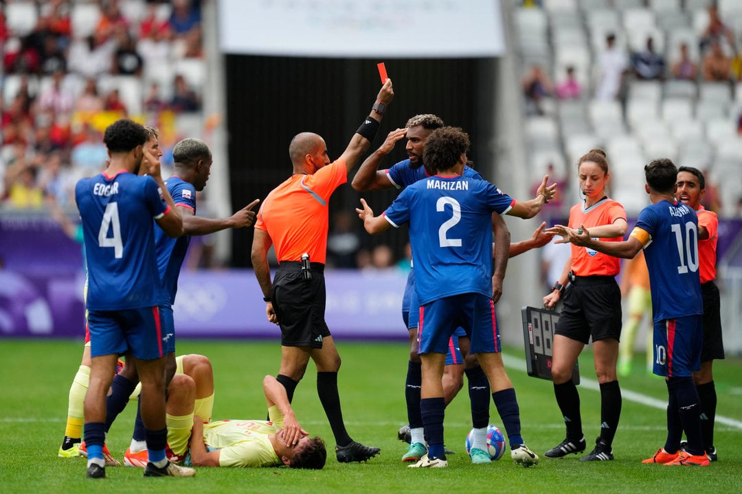 El árbitro Adel Al Naqbi (c) le saca la tarjeta roja al dominicano Edison Azcona (d) tras una acción contra Pau Cubarsí (en el suelo) durante el partido del Grupo C de fútbol masculino de los Juegos Olímpicos de París 2024 disputado este sábado en el Estadio de Burdeos. EFE/ M. Reino