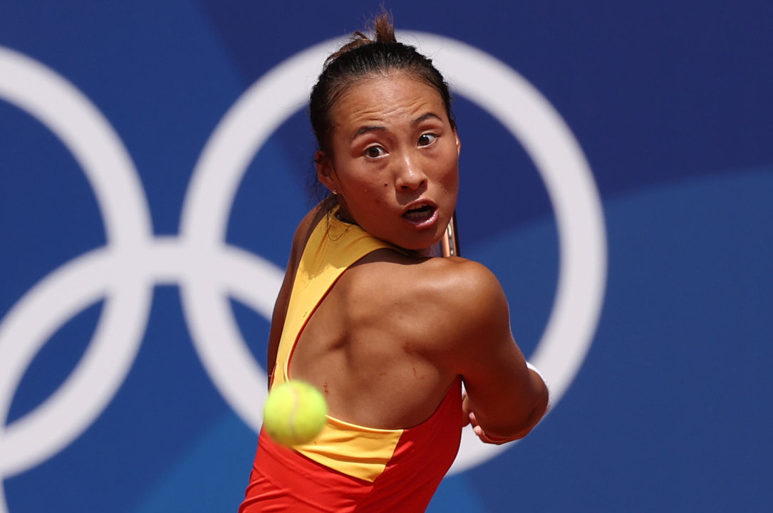 La tenista china Quinwen Zheng devuelve la bola a la polaca Iga Swiatek durante la semifinal femenina de tenis que enfrento a ambas en el marco de los Juegos Olímpicos París 2024. EFE/ Juanjo Martin