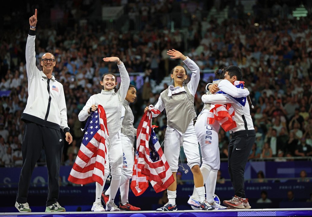 Las estadounidenses Jacqueline Dubrovich, Lee Kiefer, Lauren Scruggs y Maia Mei Weintraubjunto a sus entrenadores celebran el oro conseguido en el Grand Palais in Paris, Francia. EFE/EPA/MARTIN DIVISEK