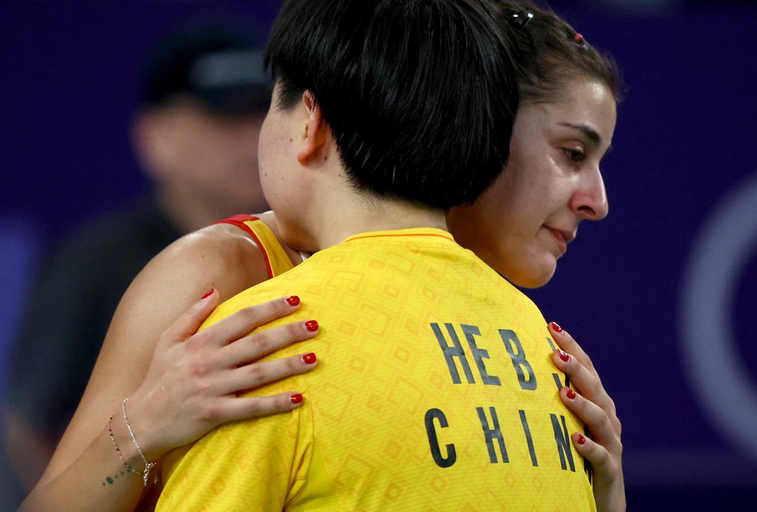 Carolina Marín abraza a su oponente He Bing Jiao de China tras retirarse con una lesión de la semifinal olímpica. EFE/EPA/DIVYAKANT SOLANKI