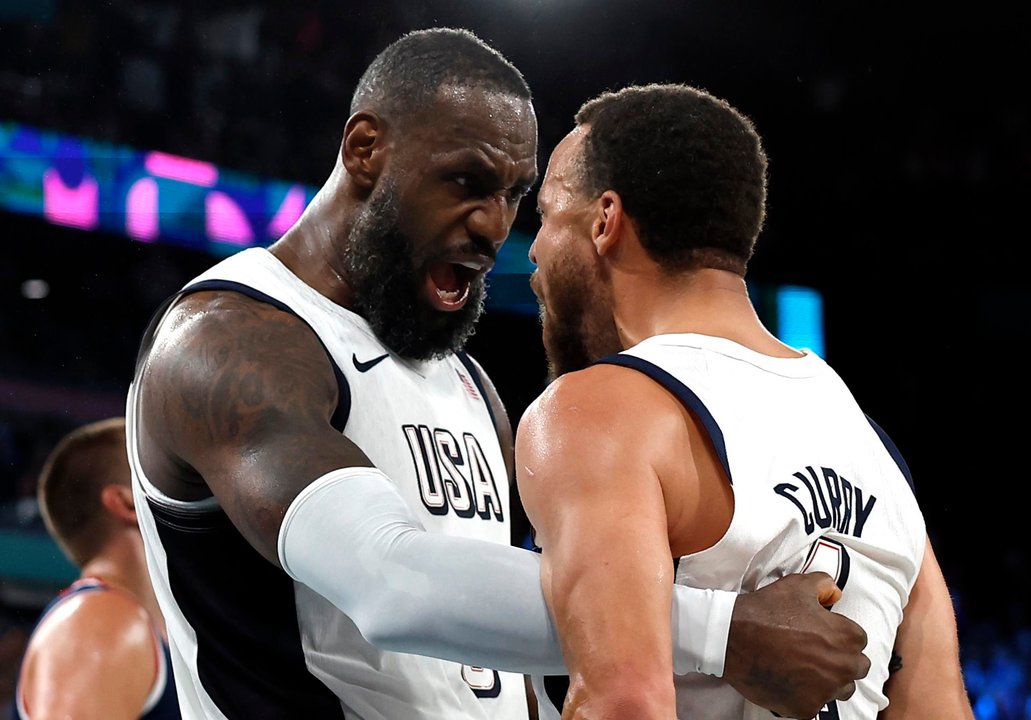 Los estadounidenses Lebron James (izq.) y Stephen Curry celebran la victoria en el partido de semifinales ante Serbia, del torneo de baloncesto de París 2024. EFE/EPA/YOAN VALAT