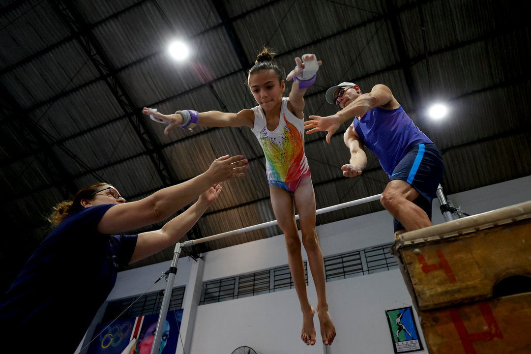 Una niña recibe ayuda para saltar durante un entrenamiento de gimnasia artística este jueves, en el gimnasio municipal Bonifácio Cardoso en Guarulhos (Brasil). EFE/ Sebastiao Moreira