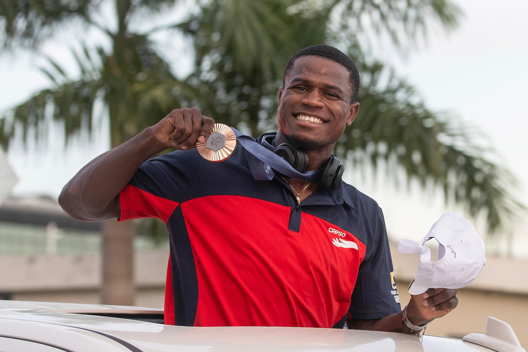 El boxeador Cristian Pinales, medallista de bronce en boxeo en los Juegos Olímpicos de París 2024, saluda durante su recibimiento,en el Aeropuerto Internacional de las Américas, en Santo Domingo (República Dominicana). EFE/Orlando Barría