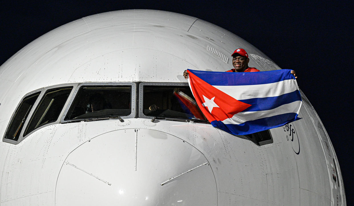 El luchador cubano Mijaín López, cinco veces campeón olímpico, sostiene una bandera de Cuba en la ventanilla del piloto a su llegada este lunes al aeropuerto José Martí de La Habana. EFE/ AFP /Adalberto Roque/POOL